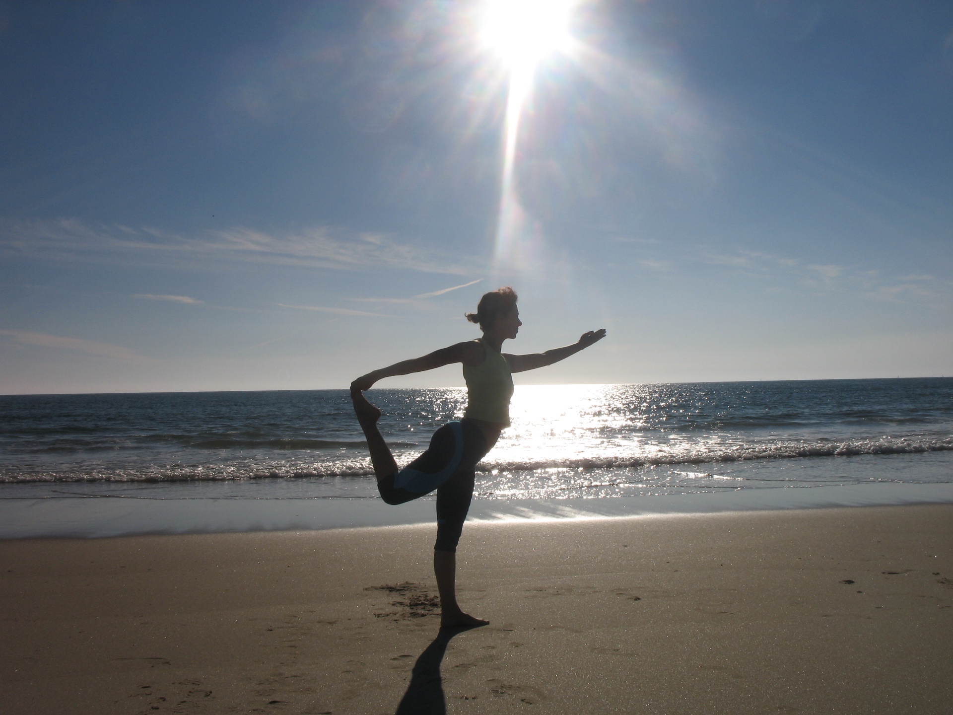 Sandra em postura do dançarino (Natarajasana) na praia