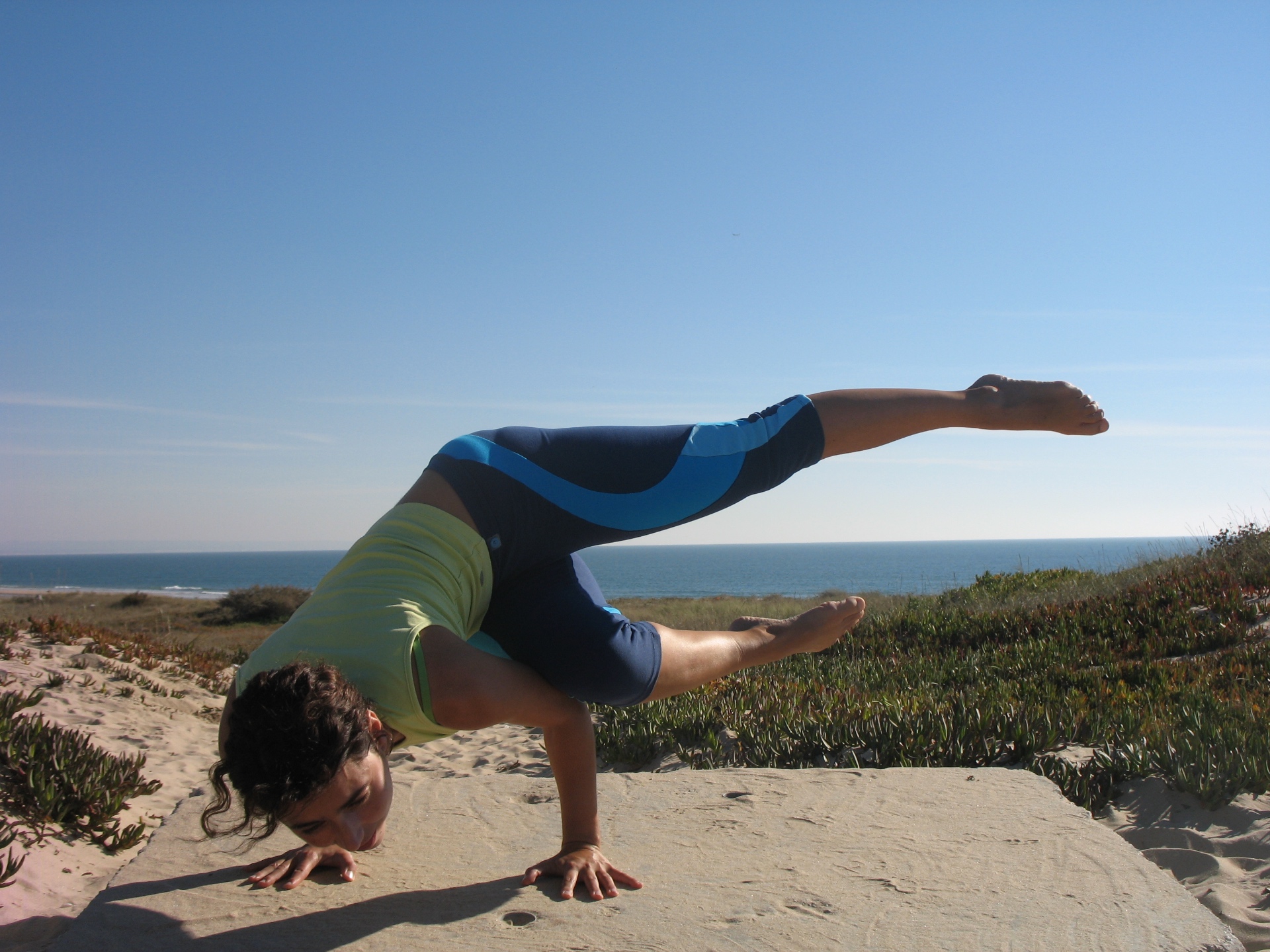 Sandra em postura de equilíbrio de braços (Bhujapidasana) nas dunas