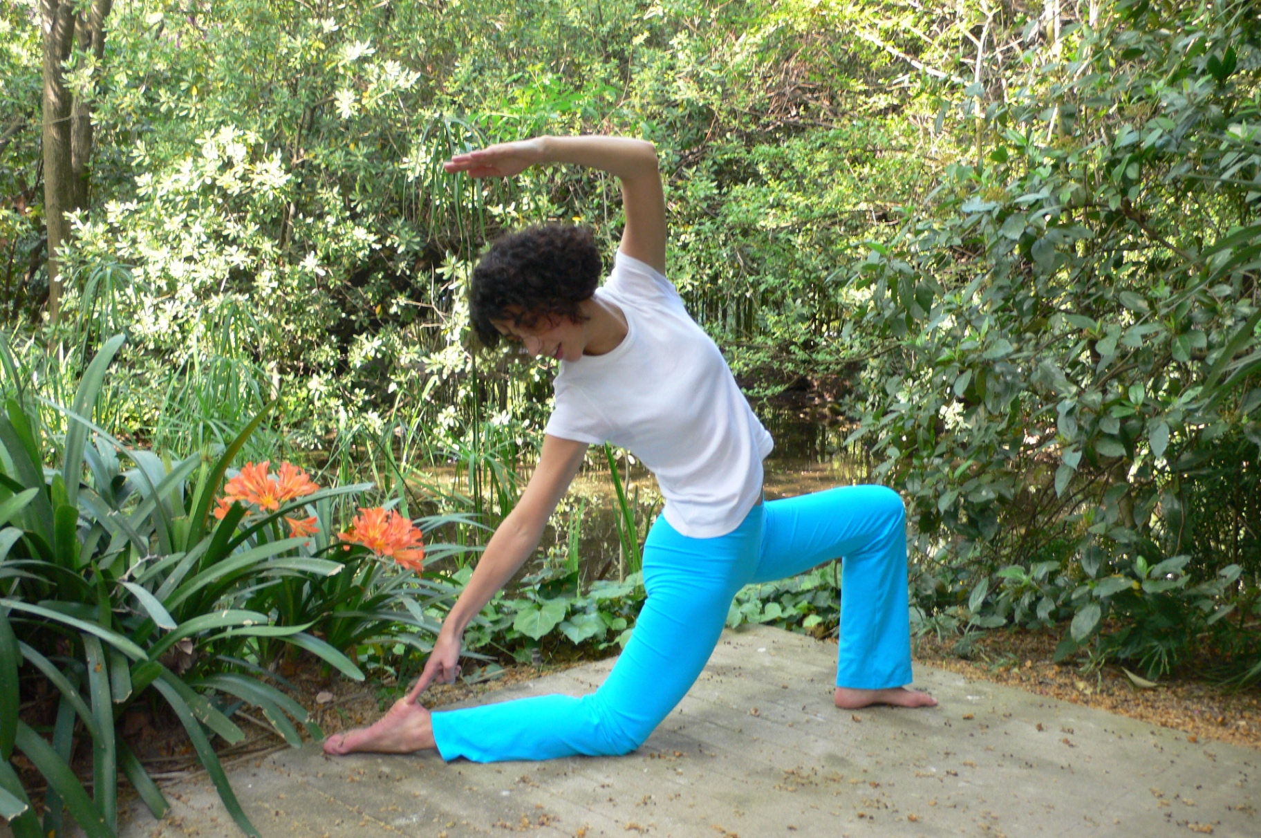 Sandra Tomé numa pose de Yoga ao ar livre, rodeada de vegetação
